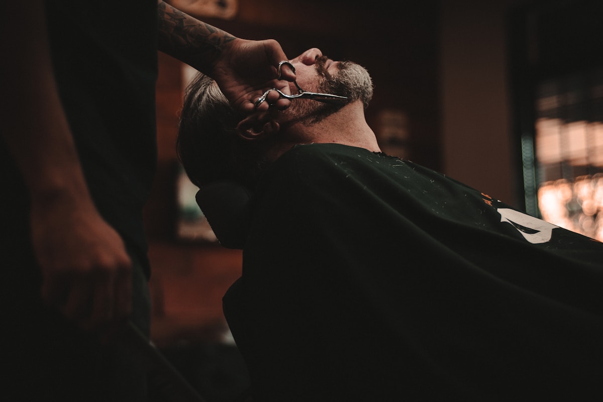 Barbero profesional realizando un corte fade en barbería moderna